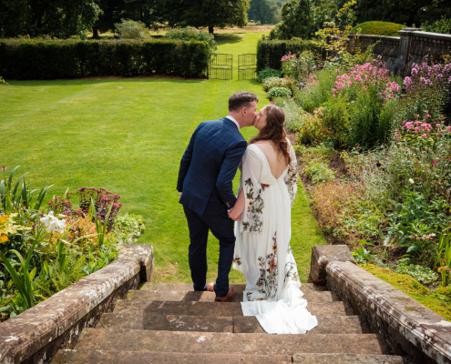 Summer Springkell Wedding Photos. Bride and Groom Flora and David sneak a kiss on the steps at Springkell.